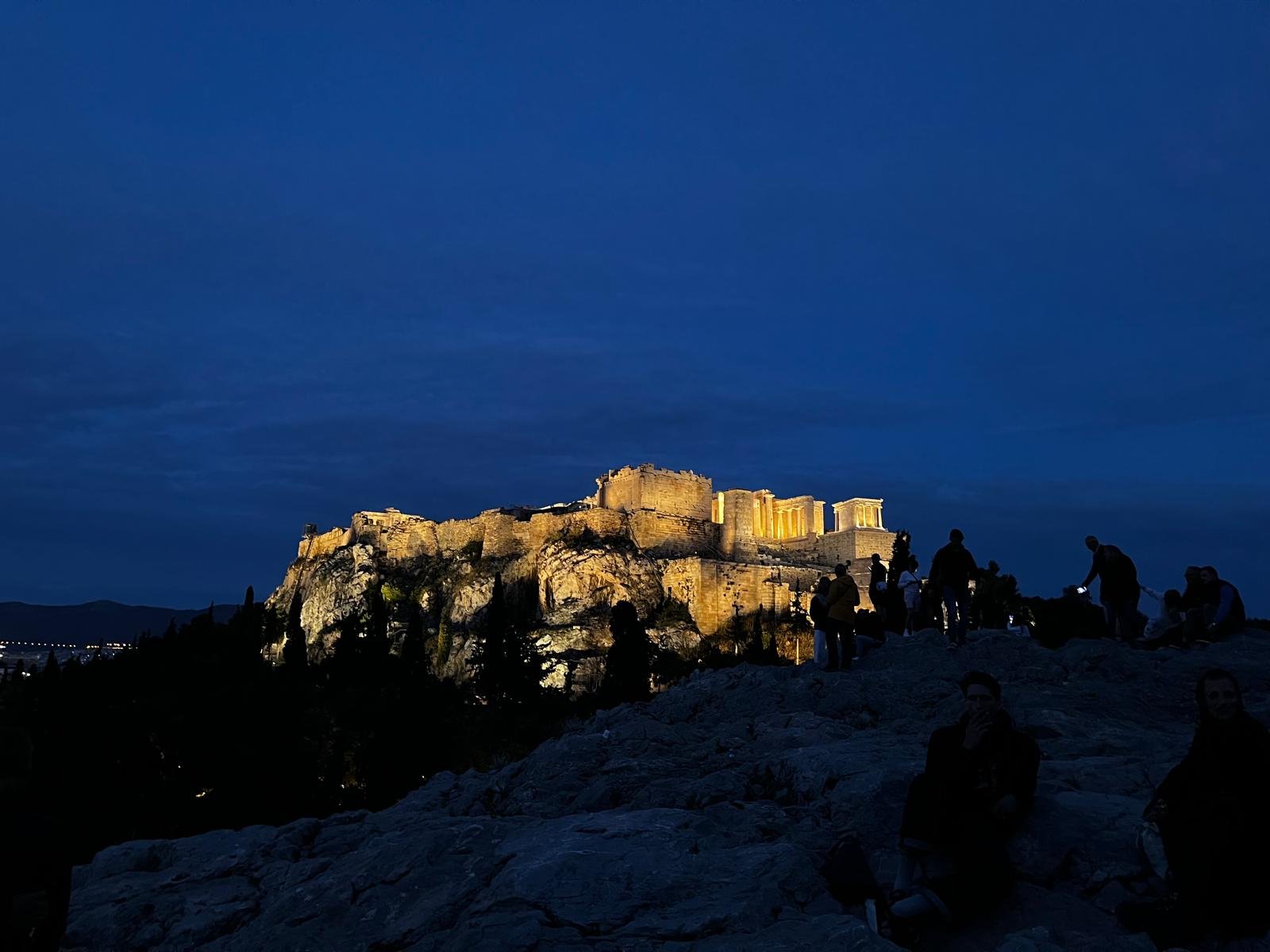 The Acropolis of Athens illuminated at night — viewed from Filopappou Hill at dusk