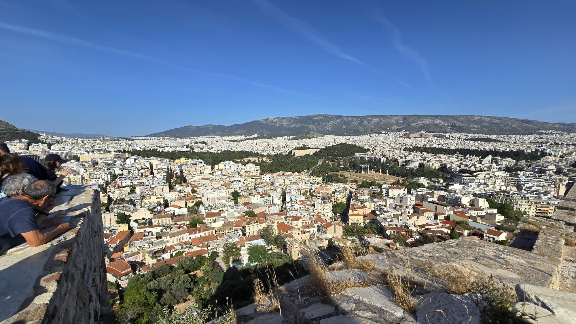 The view over Athens from the Acropolis slopes — the sprawl of the city beneath the surrounding mountains