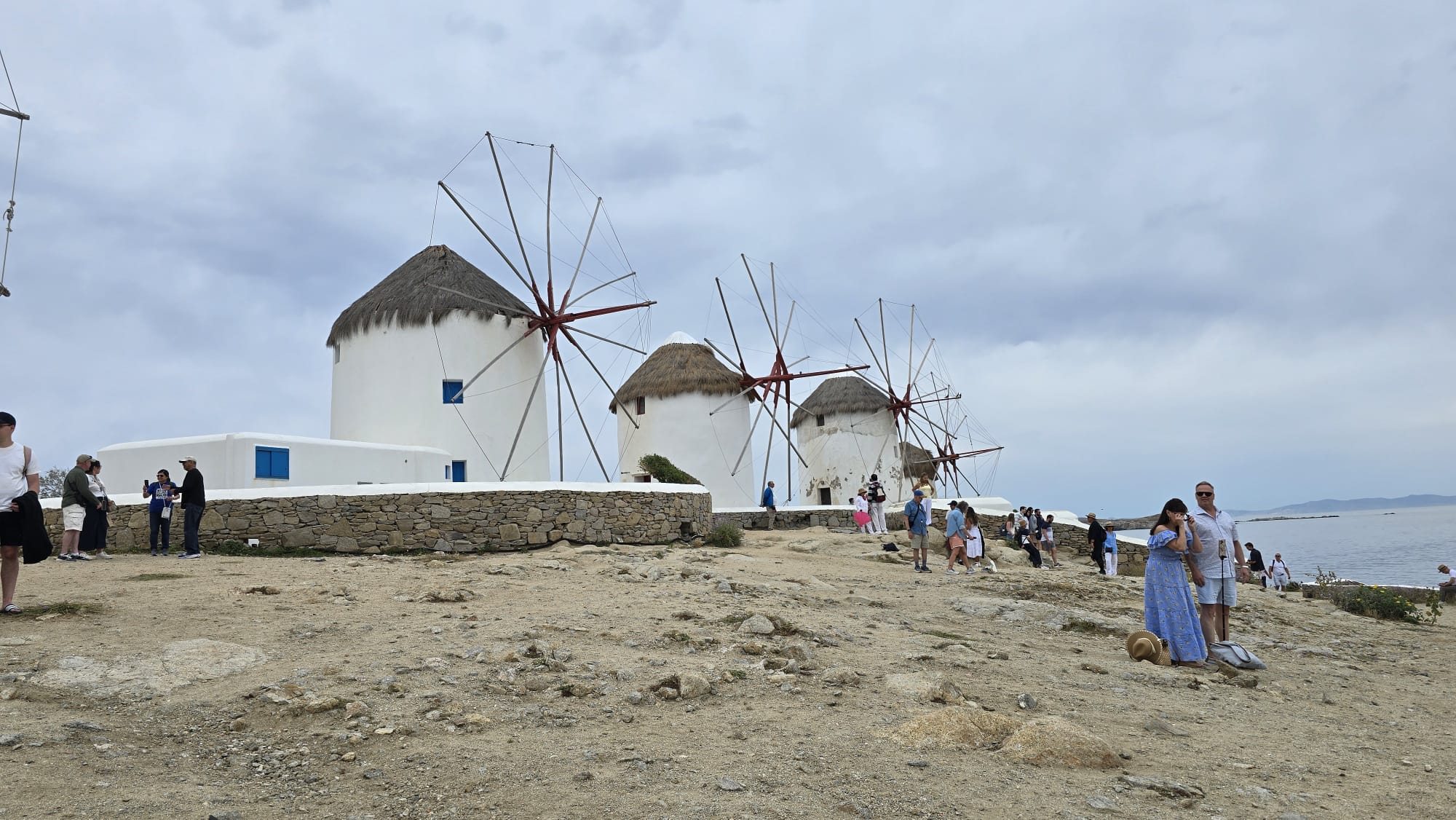 The iconic windmills of Mykonos standing in a row on the hill above the town, whitewashed against a deep blue sky