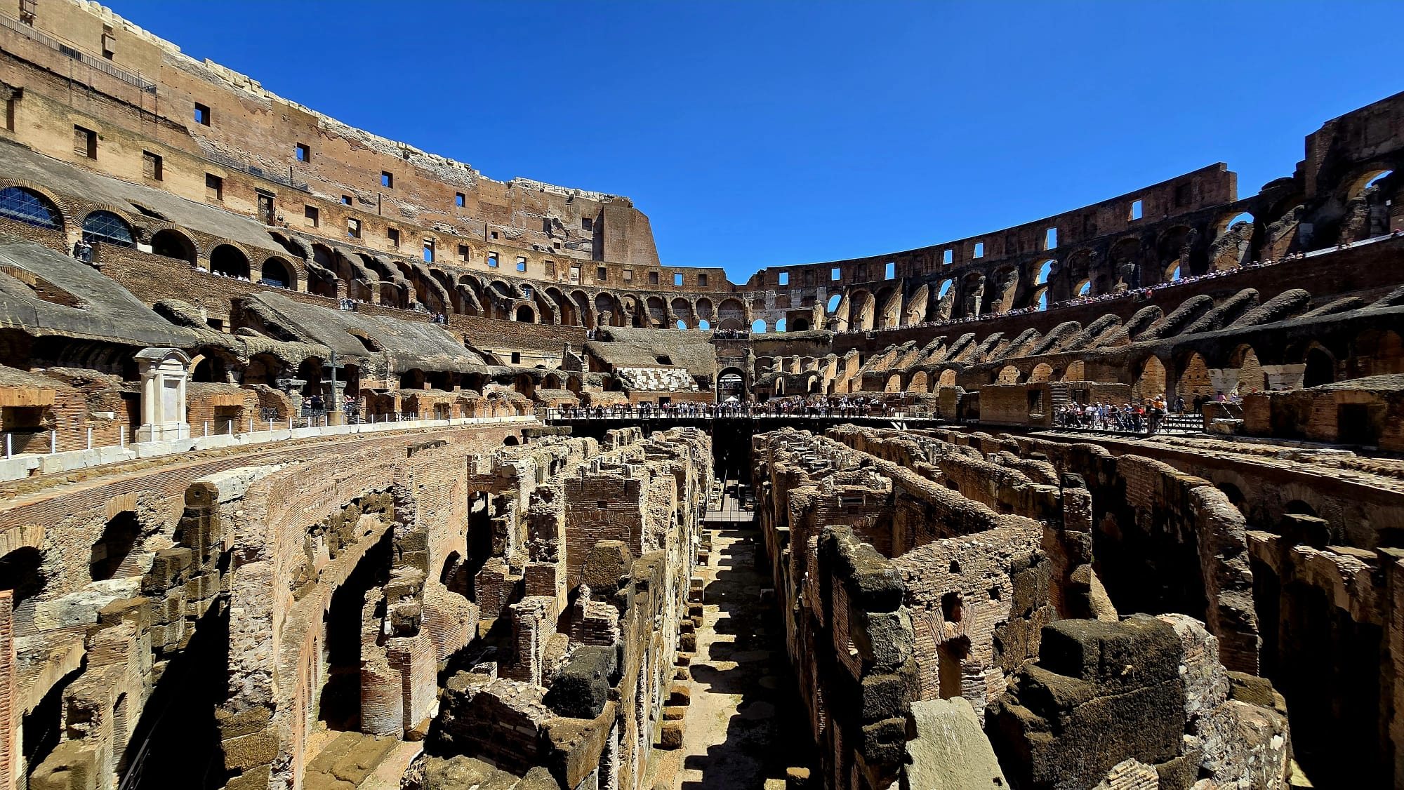 The Colosseum in Rome seen from outside — the great curved tiers of arches lit warm against a clear sky