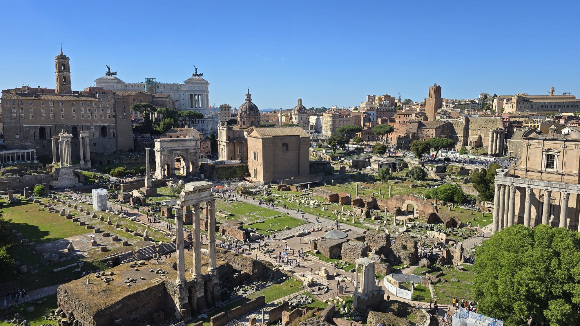 The Roman Forum — broken columns, arches and temple ruins stretching across the ancient city centre under a bright sky