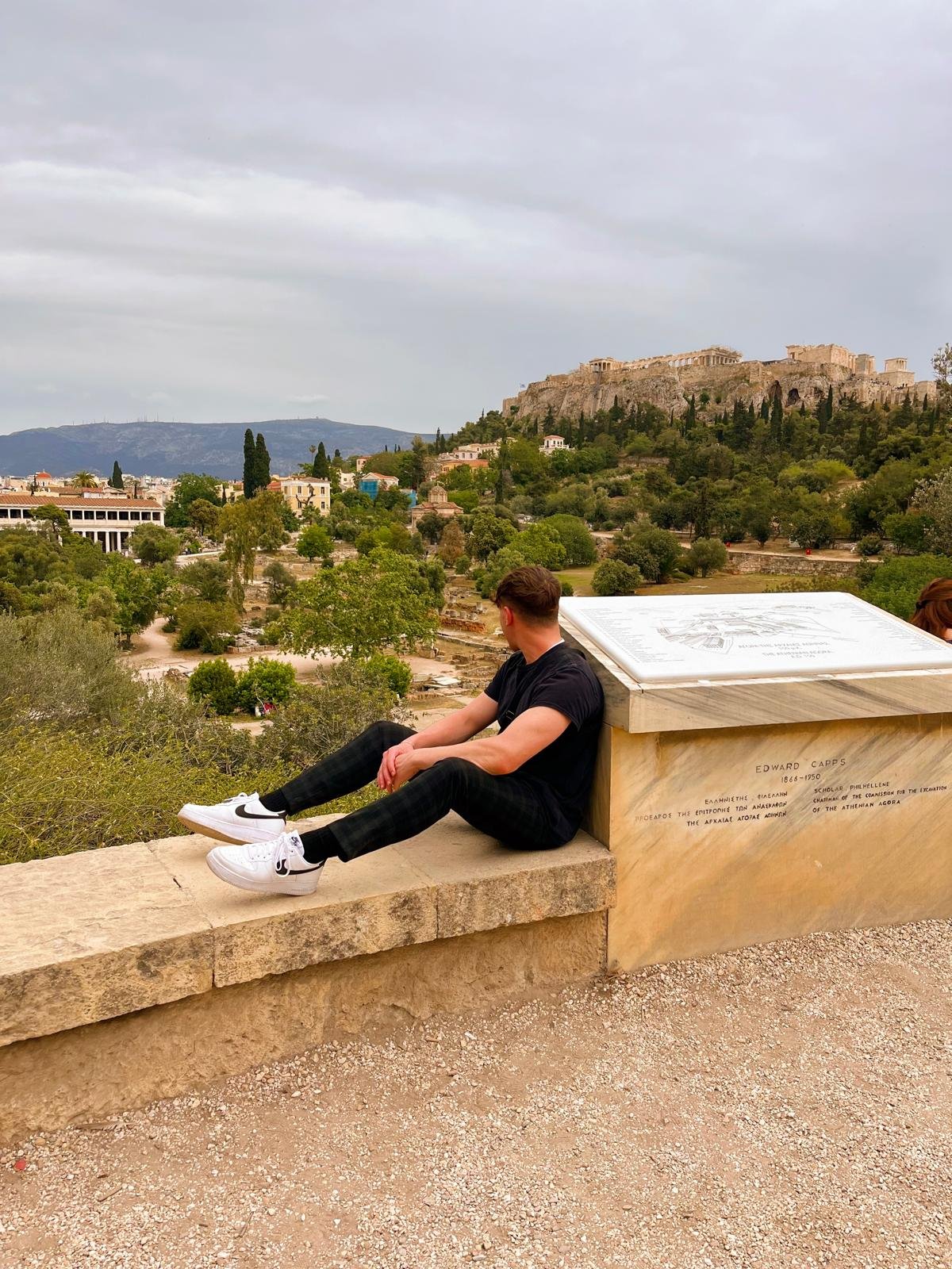 Yaron sitting overlooking the ancient Athenian Agora with the Acropolis visible behind