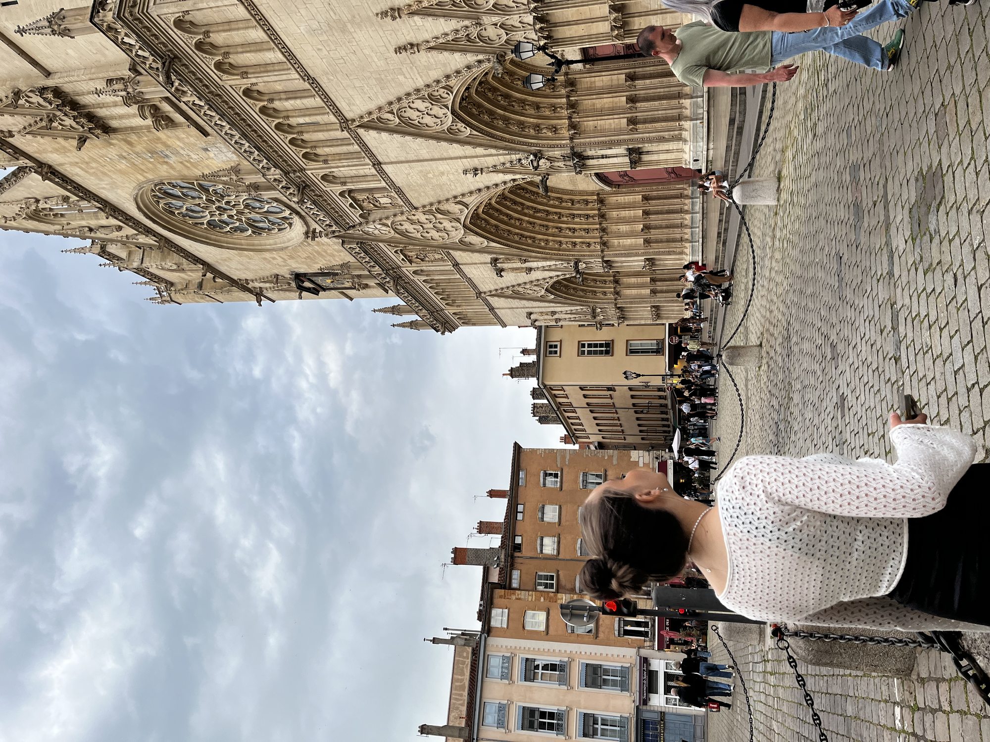 A woman in a white dress walking up the cobblestone steps toward the Gothic facade of Cathédrale Saint-Jean in Vieux-Lyon at golden hour
