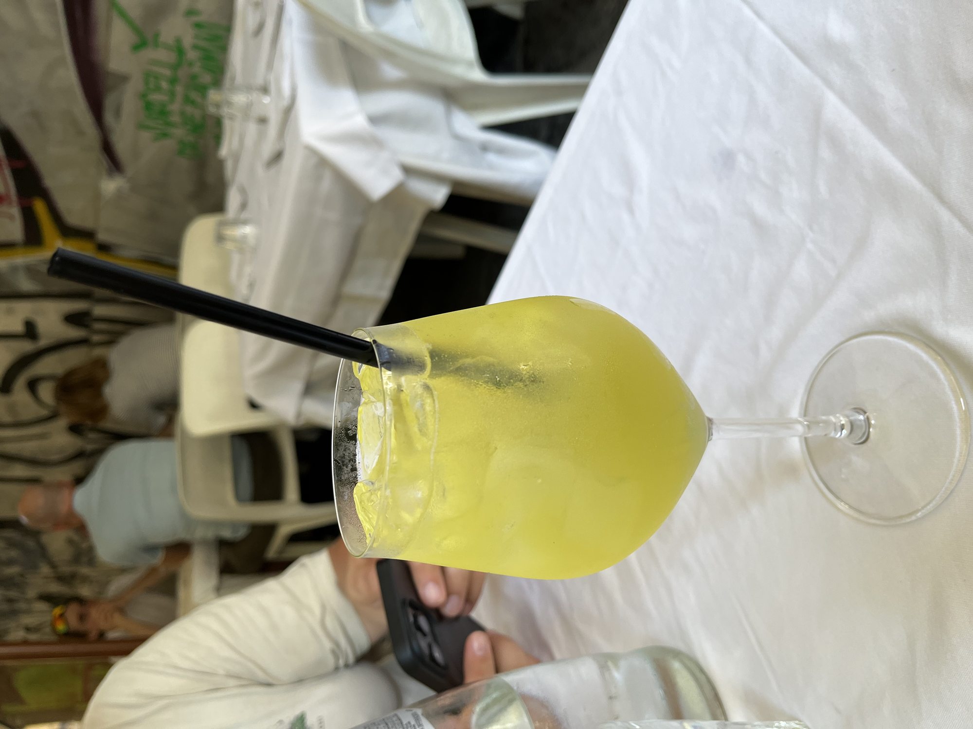 A frozen Aperol-style spritz in a chilled glass with a black straw on a white tablecloth at a pizzeria in central Naples