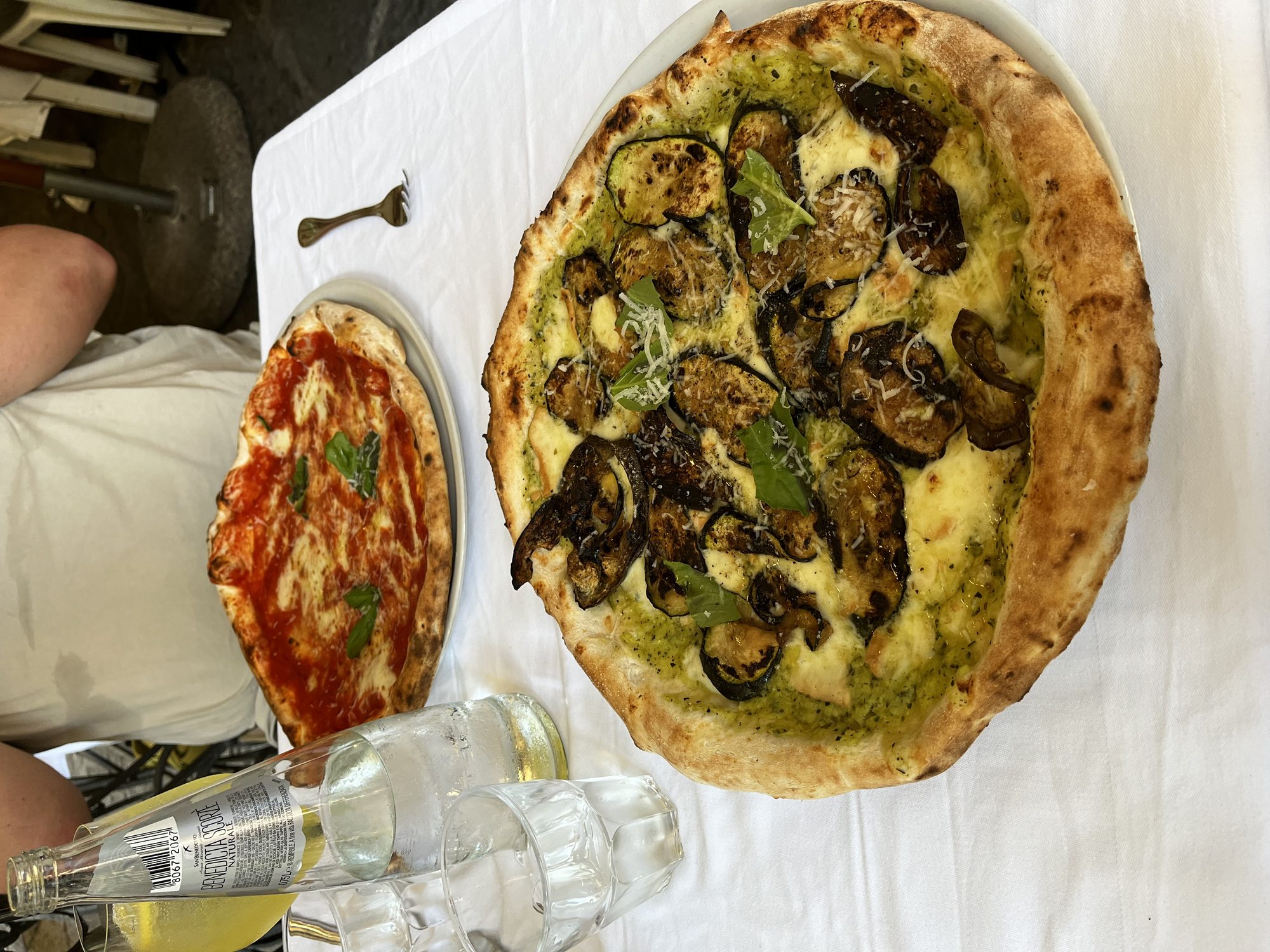 A Neapolitan pizza with grilled mushrooms, pesto, mozzarella and parmesan beside a margherita pizza on a white tablecloth at Antica Pizzeria Port'Alba