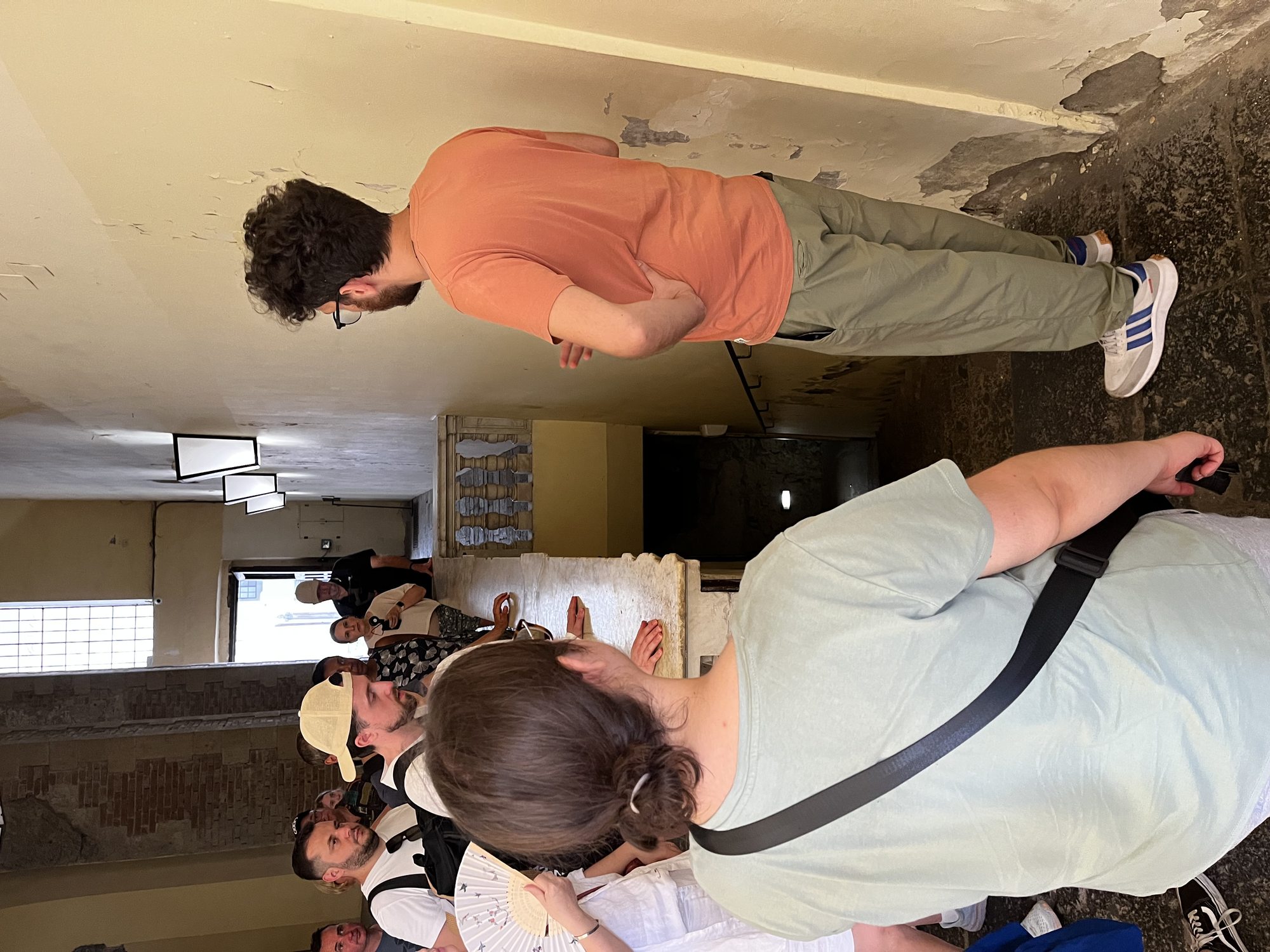 A guided tour group standing in a peeling-plaster cellar at the start of the Napoli Sotterranea route