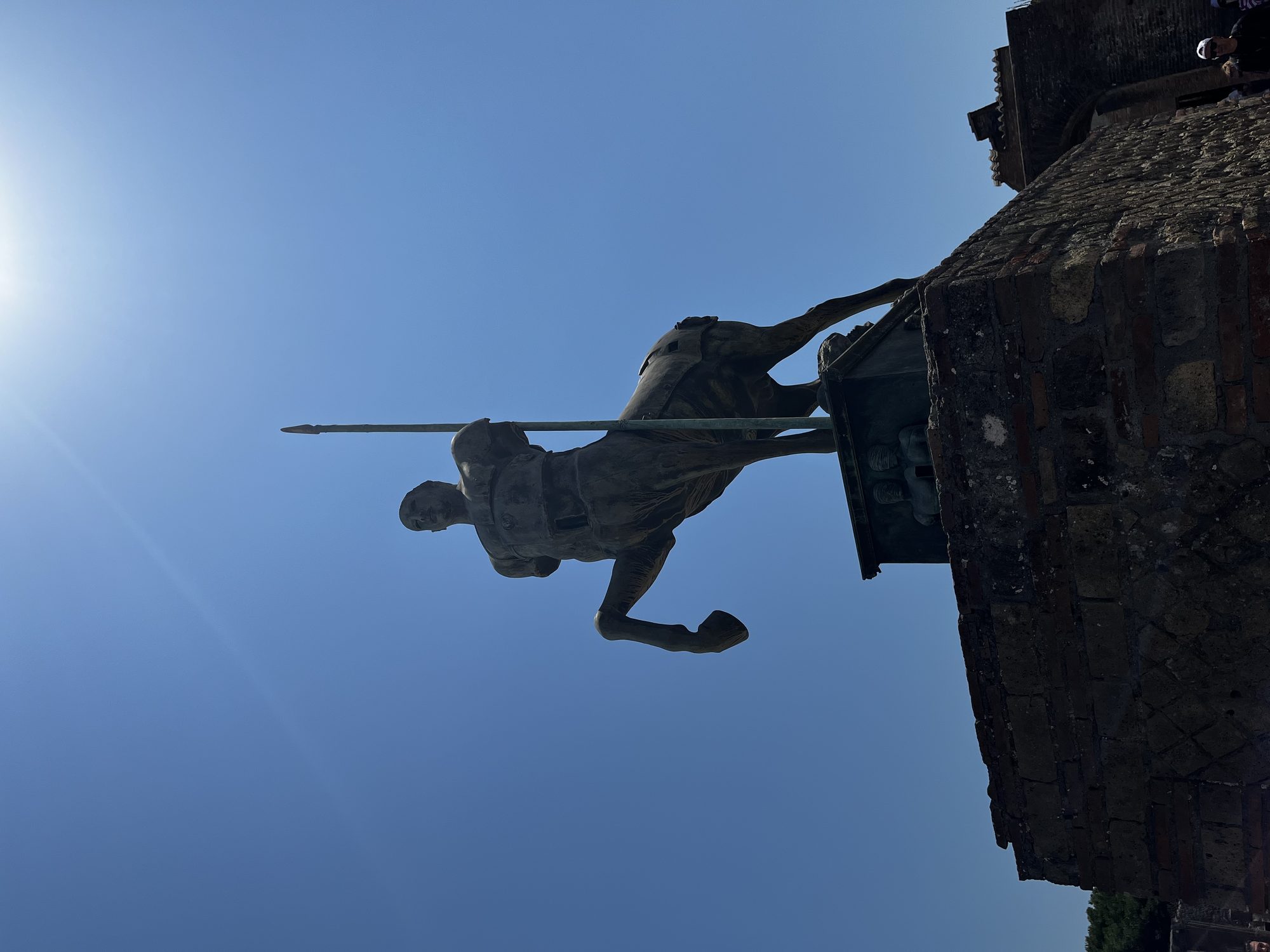The Centaur statue at Pompeii's Forum silhouetted against the blazing midday sun — all four legs raised, spear pointing skyward