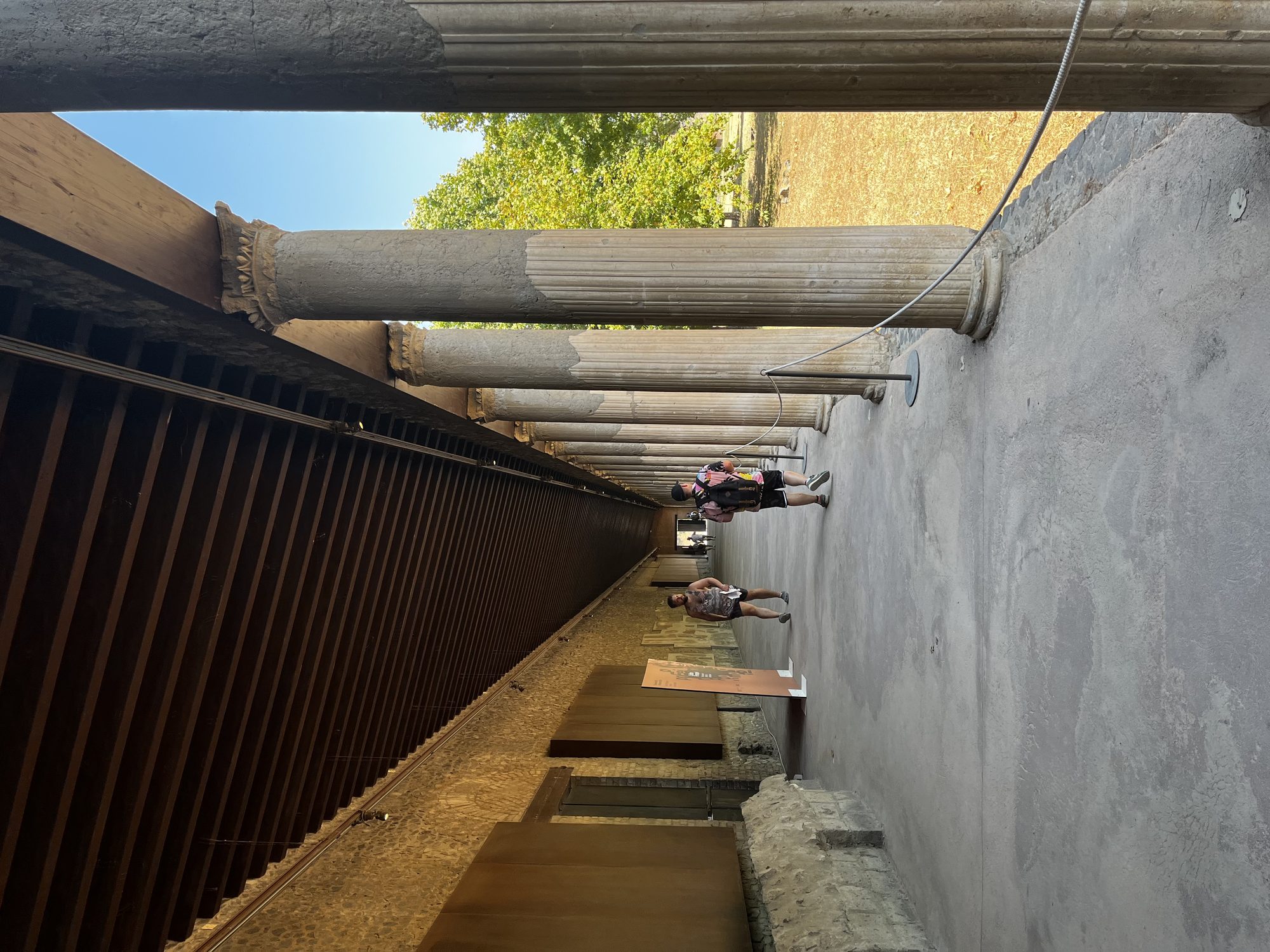 The long colonnade of the Pompeii Palestra — the ancient gymnasium, with fluted columns stretching into the distance under a wooden roof