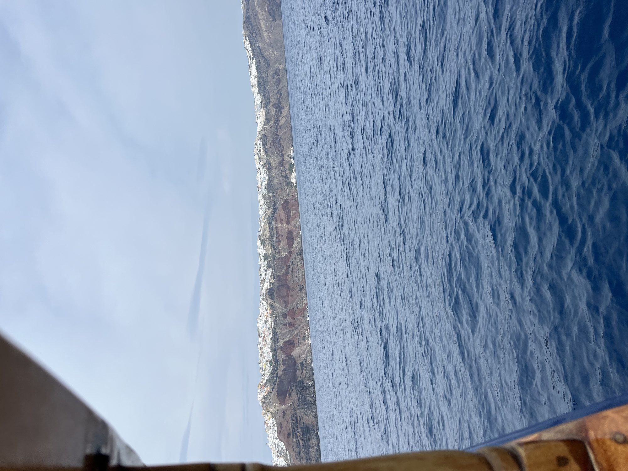 Arriving in Santorini by ferry — the caldera cliffs and white villages seen from across the Aegean Sea