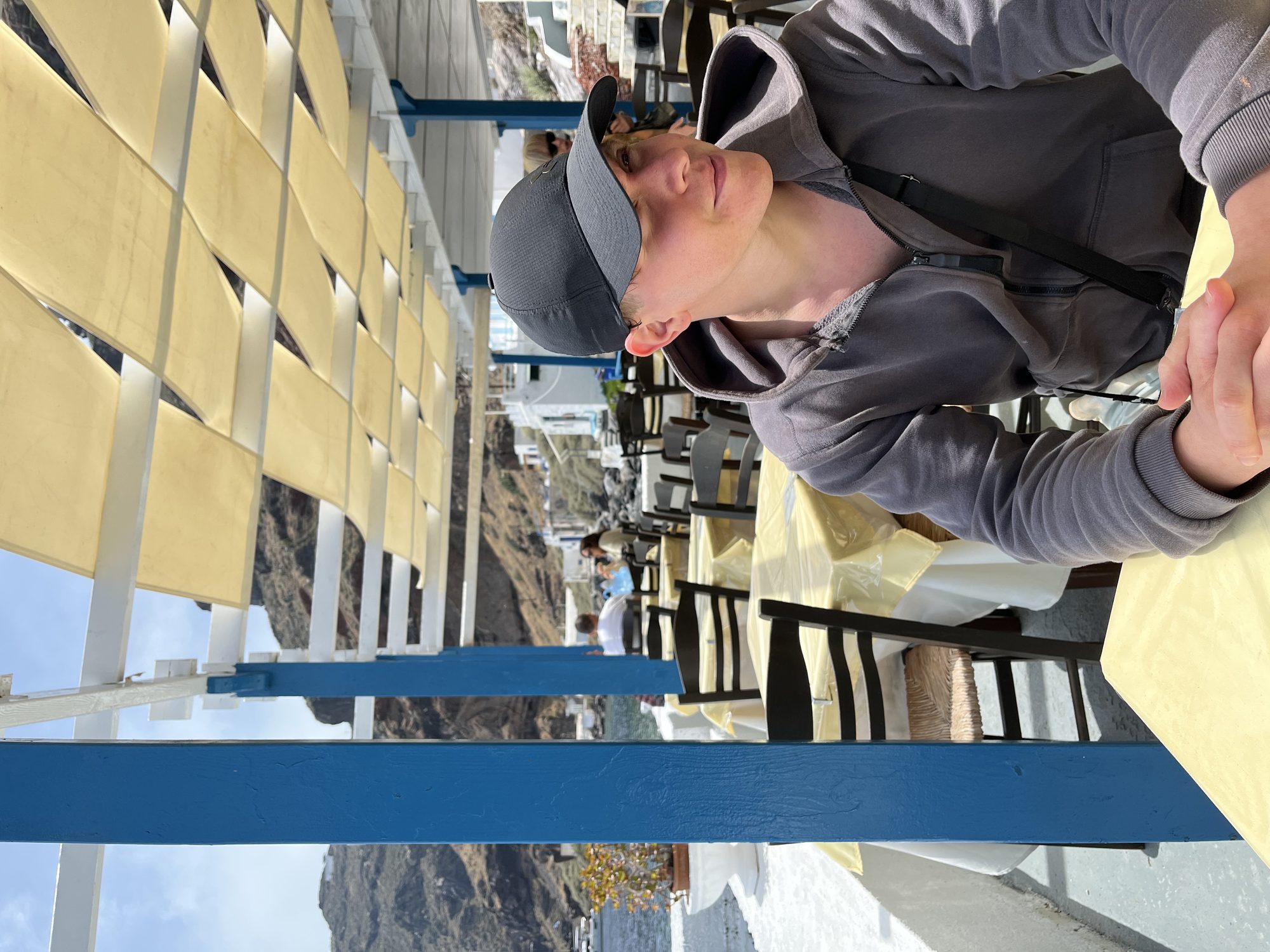 Yaron at a caldera-side restaurant in Santorini — blue and white traditional taverna by the water