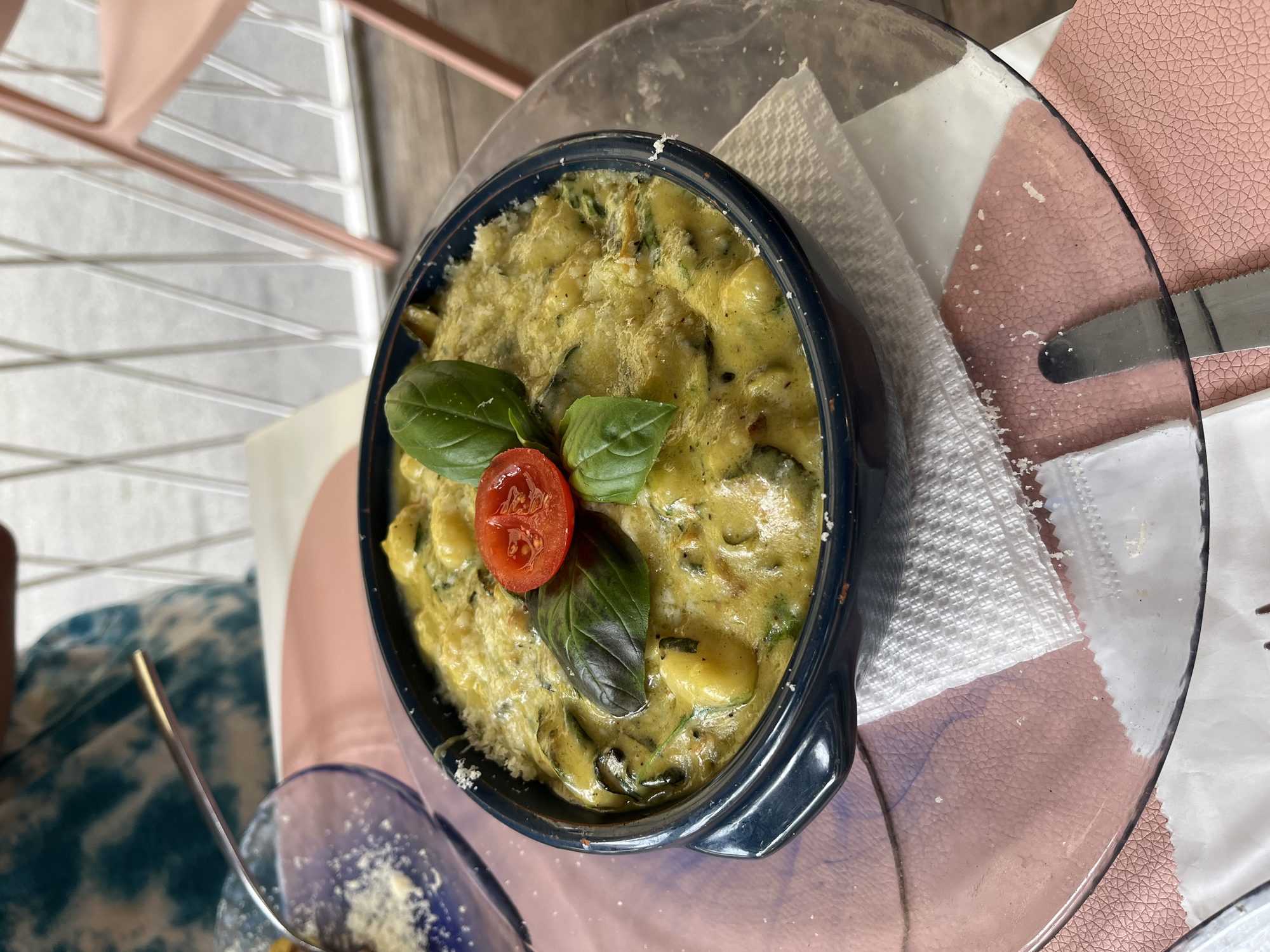 Baked gnocchi in a blue ceramic dish at a Sorrento restaurant, fresh basil and cherry tomato