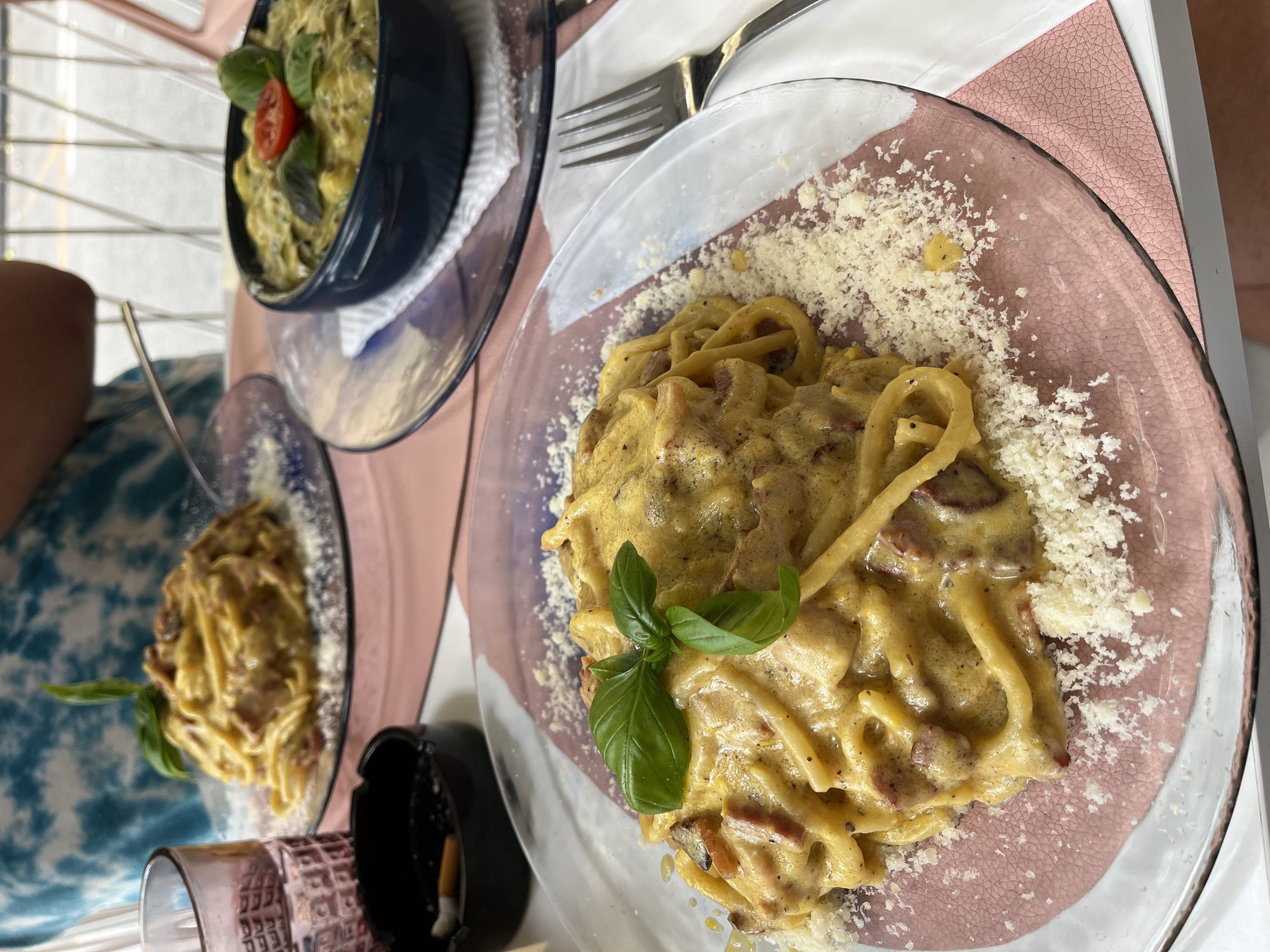 Homemade tagliatelle carbonara at a Sorrento restaurant — three plates, fresh basil, parmesan